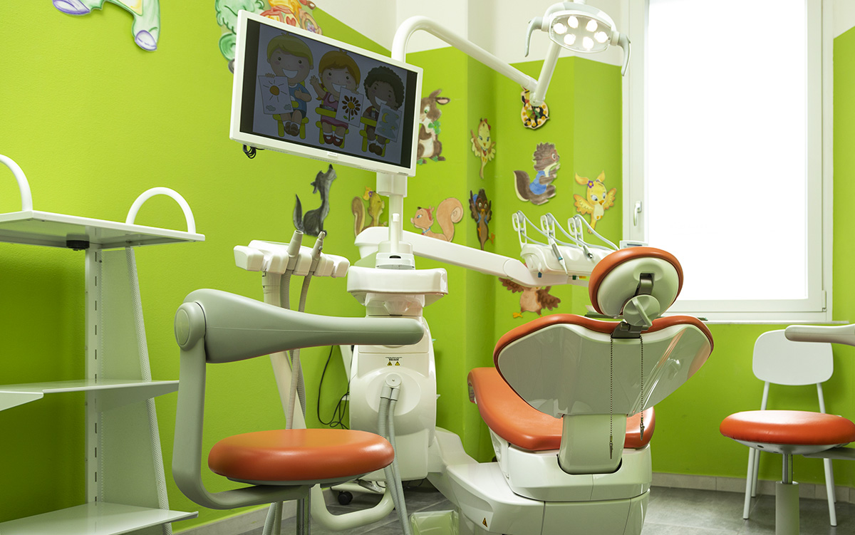 Sala operativa pediatrica colorata e accogliente dello Studio Ferman For Kids, con poltrona arancione e monitor che mostra immagini di bambini, ideale per la prima visita